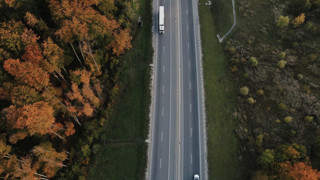 semi truck aerial view trees lining the road